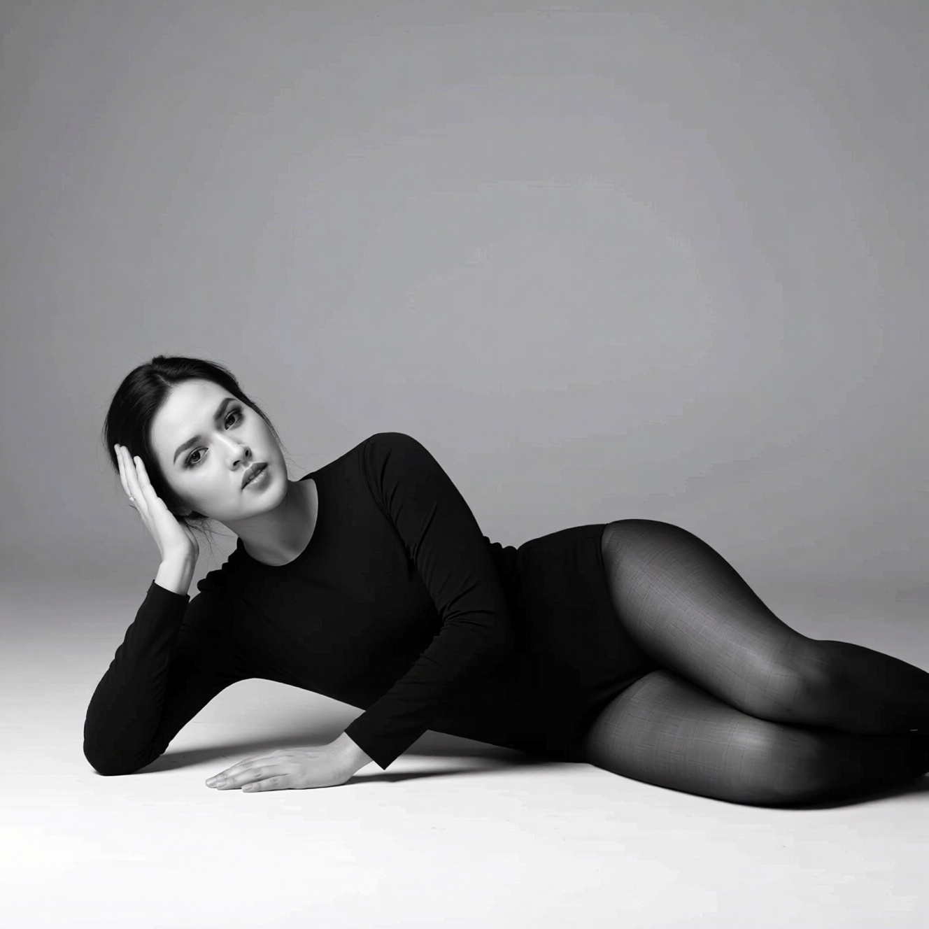 Black and white studio fashion image of an woman named ohwx with sleeked-back hair wearing a black long-sleeved bodysuit a...