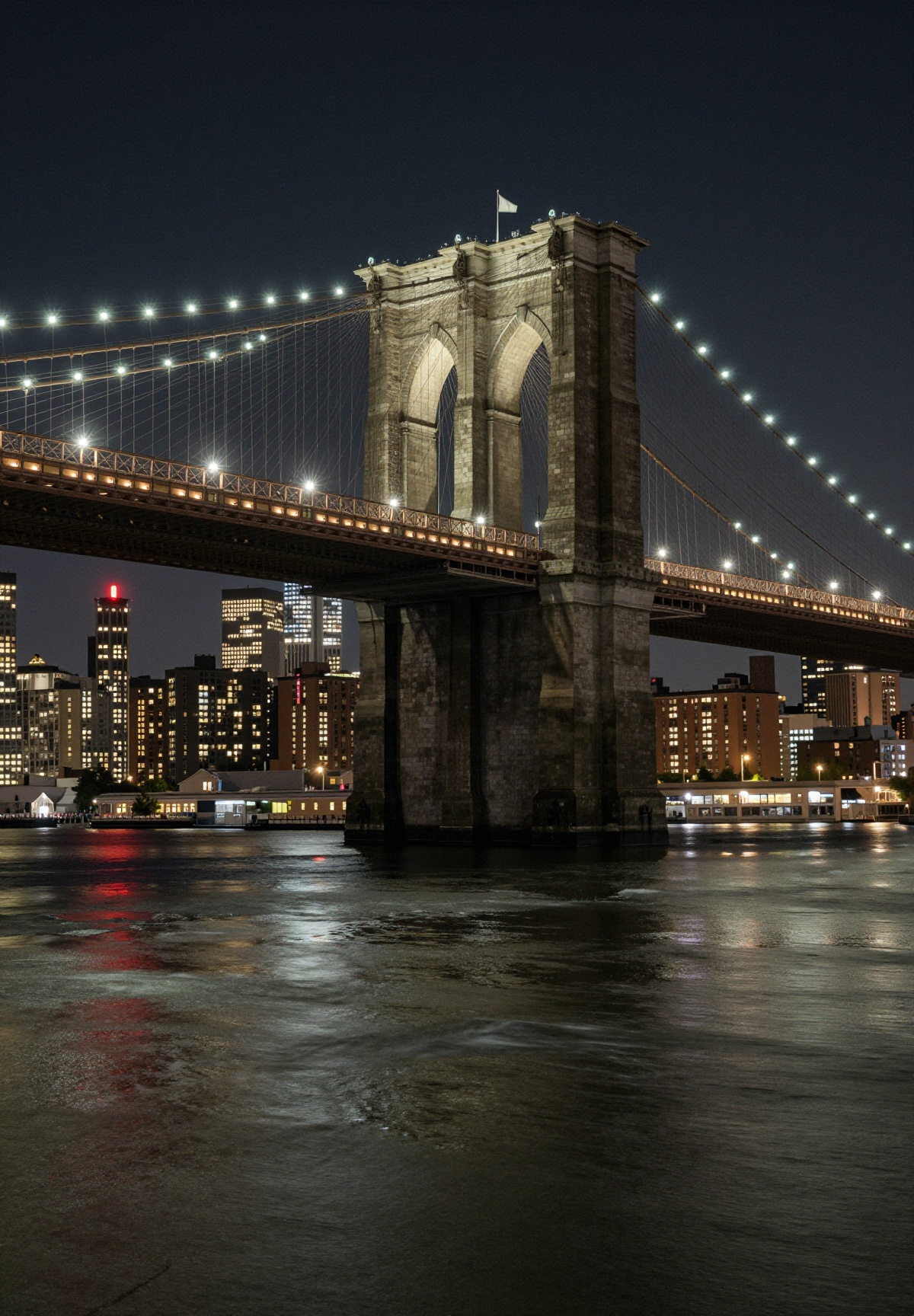 This is a stunning nighttime photograph capturing the Brooklyn Bridge from a vantage point on the water,  likely from a bo...