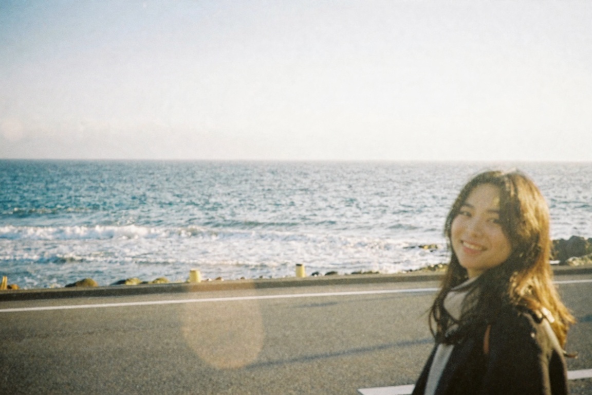 retrodigicam,  A dreamy digicam-style photo of a quiet seaside road in Japan,  running parallel to the ocean under soft af...