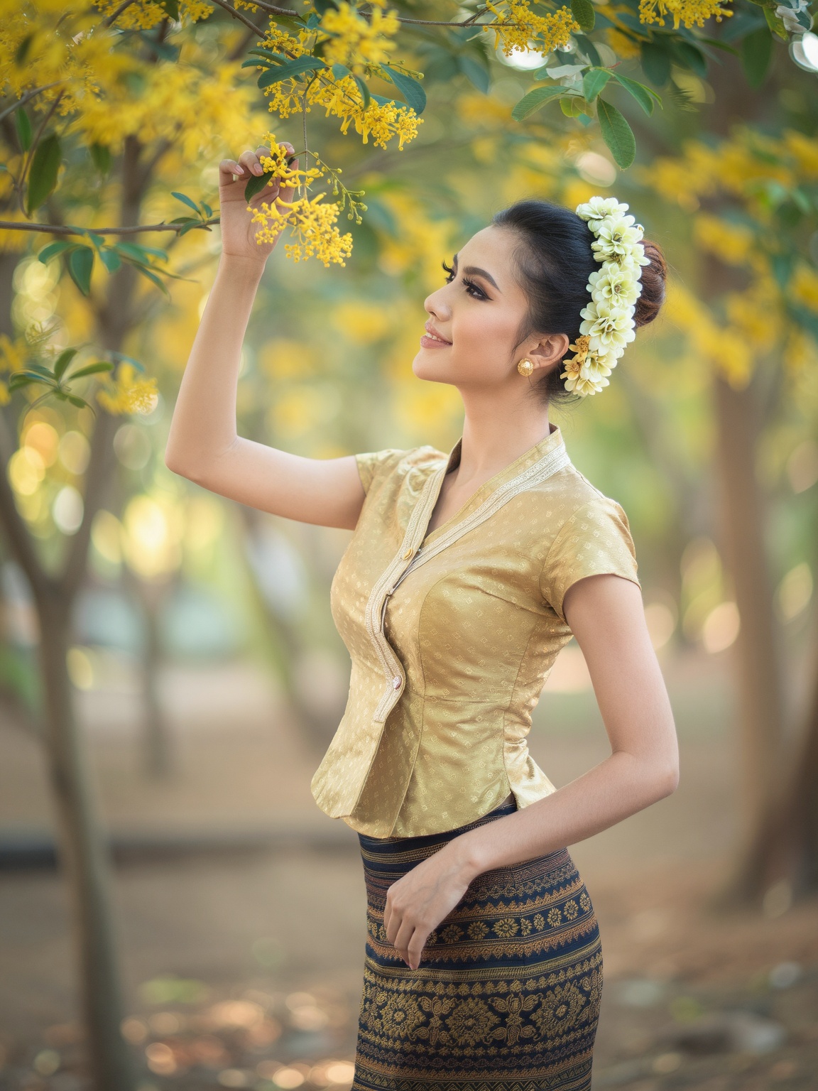 thingyan_lady,  A beautiful Myanmar girl in a short-sleeve fitted golden blouse and a patterned longyi. Her hair is neatly...