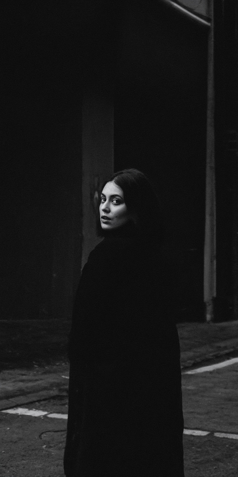 A slow,  deliberate turn of the woman's head to the left dominates the frame,  capturing a dark and mysterious atmosphere....