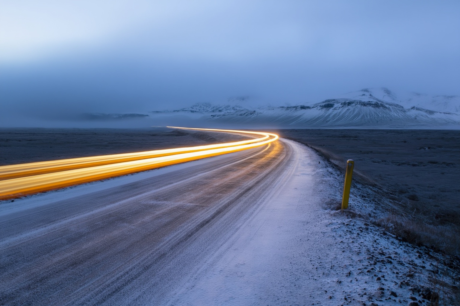 aurelmanea3z photography. A snowy landscape with a road curving into the distance. The road is partially covered with a th...