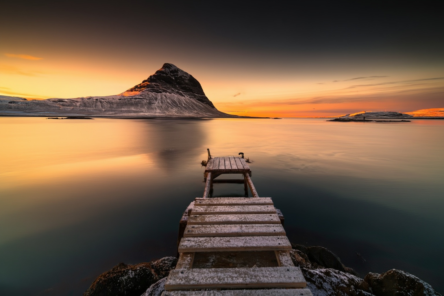 aurelmanea3z photography. A seascape at sunset,  with a wooden dock extending into the calm water. The dock leads to a sma...