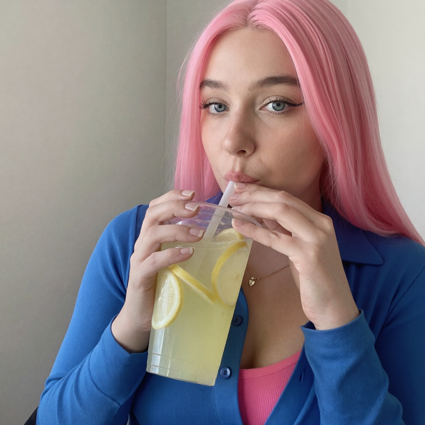 A bright and vibrant photo portrait of a woman with pink hair,  wearing a blue shirt and a pink top underneath. She is dri...