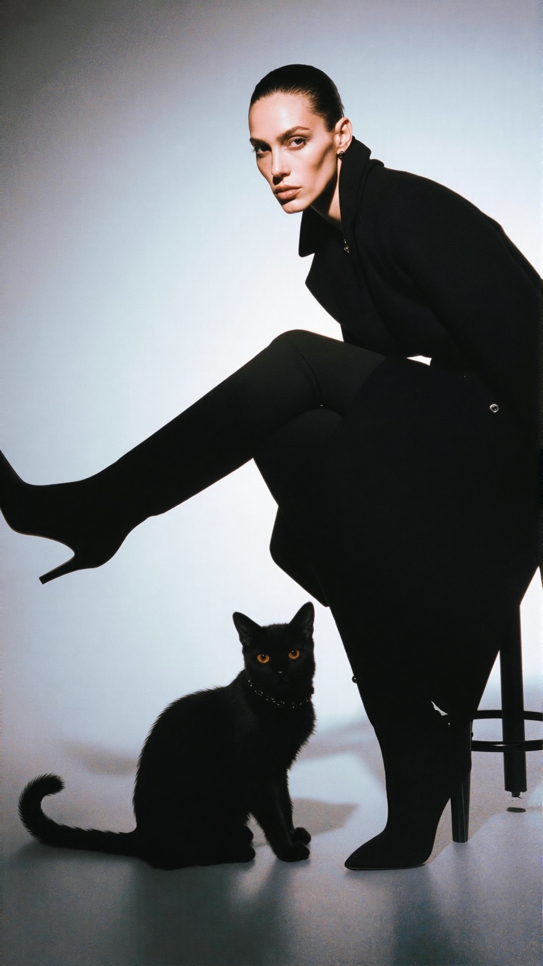 A woman with a black cat| A slender model with sharp cheekbones and dark hair slicked back into a high ponytail,  expressi...