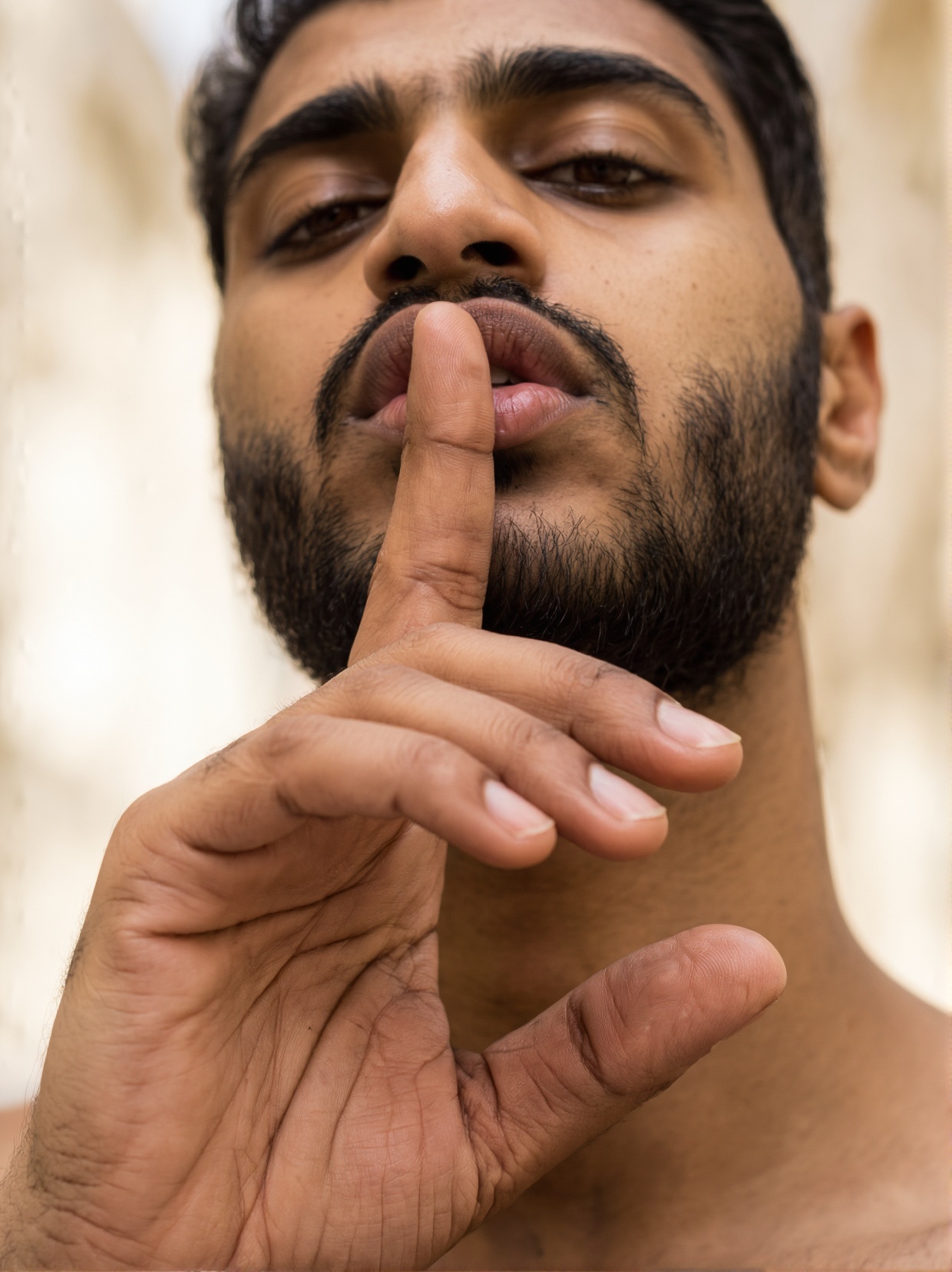 A close-up photograph taken from below and slightly from side,  of a man doing a shushing pose with his index finger on hi...