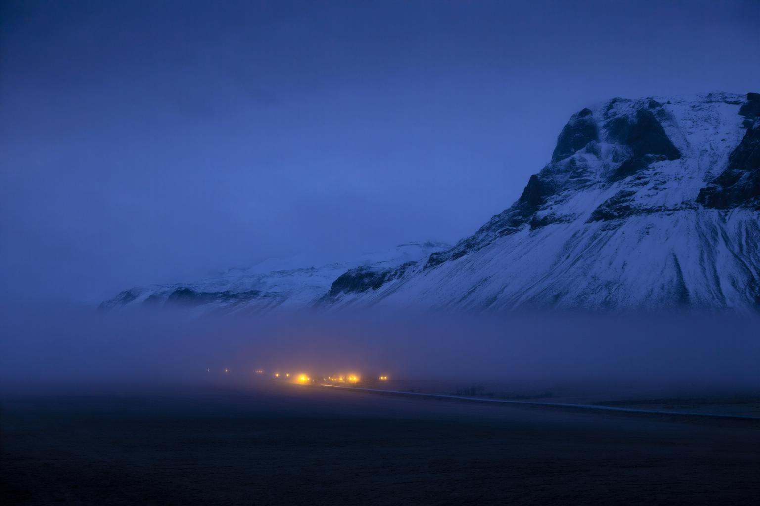 aurelmanea2q photography. A landscape at dusk or nighttime. The foreground consists of a flat,  dark terrain,  possibly a...