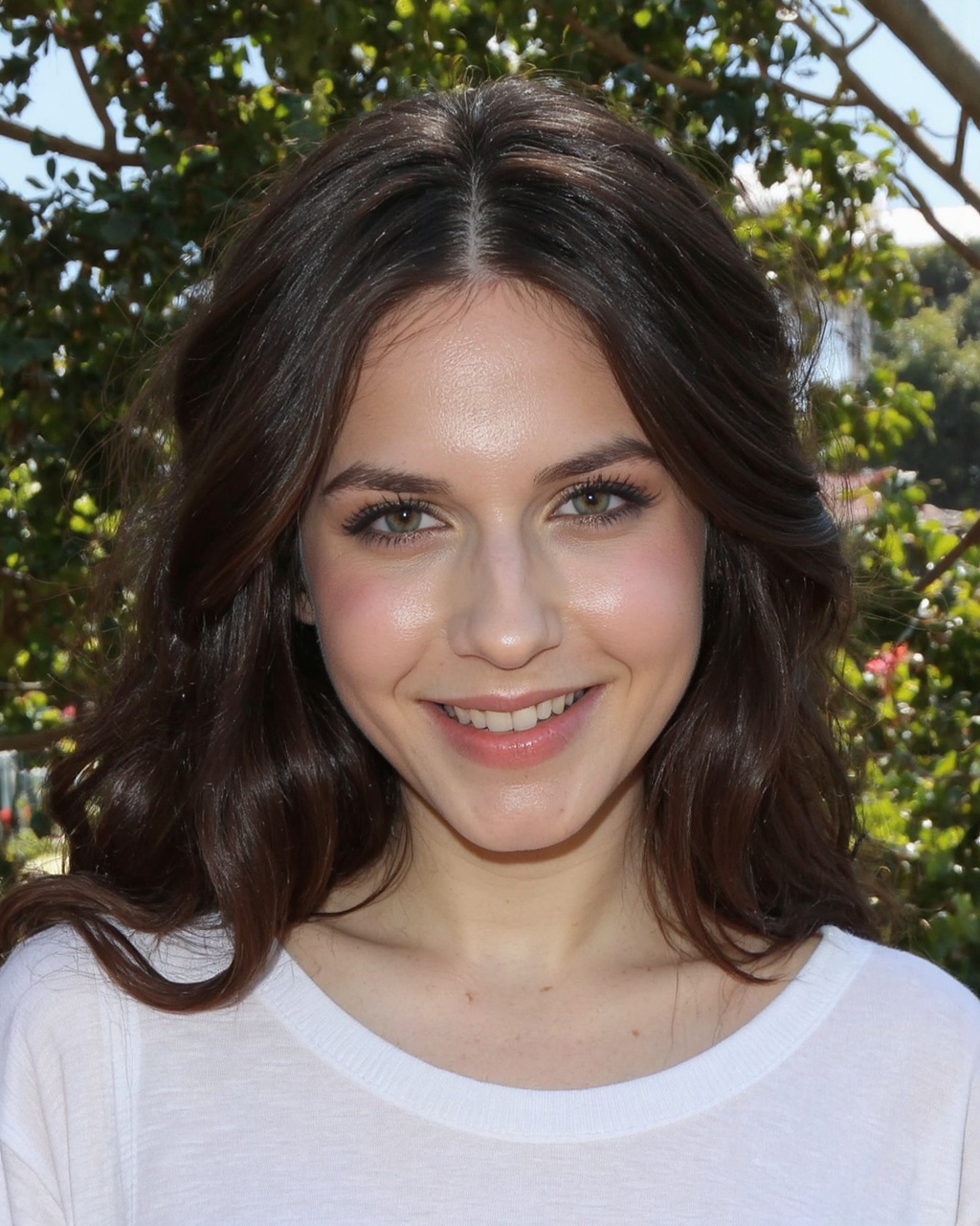 A close-up portrait of erin_sanders outdoors. She has long,  dark brown hair and blue eyes. She wears a white t-shirt. The...