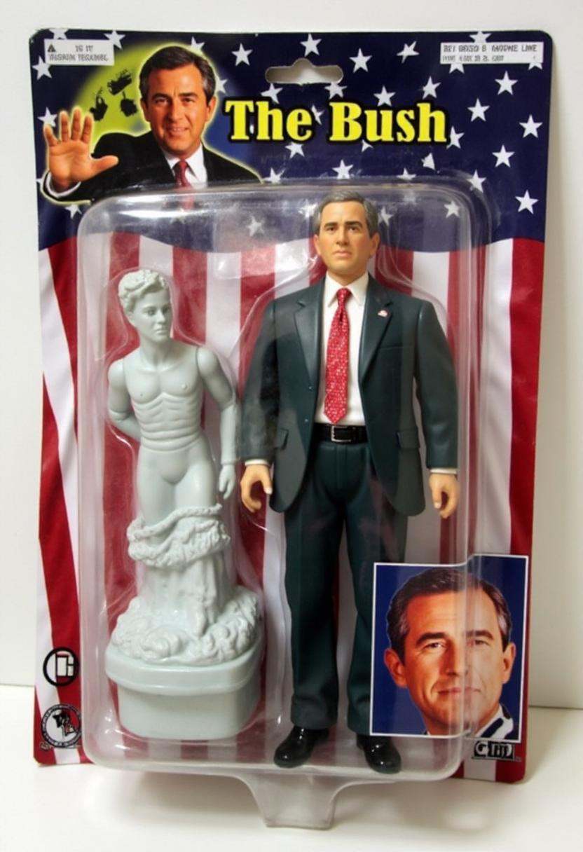 The image is a photograph of a packaged action figure of George W Bush. on Tensor.Art