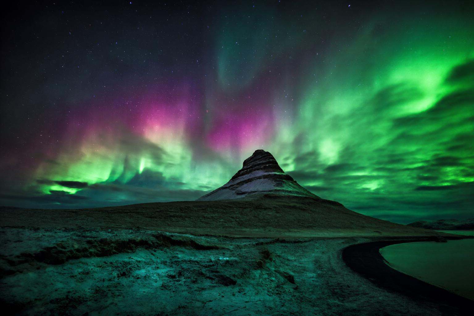 aurelmanea2q photography. A nighttime landscape with a prominent mountain peak in the center,  partially covered in snow....