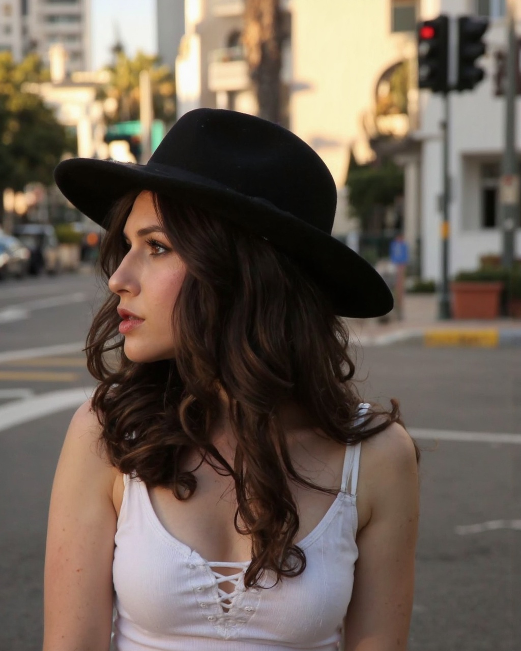 A portrait of erin_sanders captured in a side profile. She wears a wide-brimmed black hat and a white,  lace-up top. Her l...