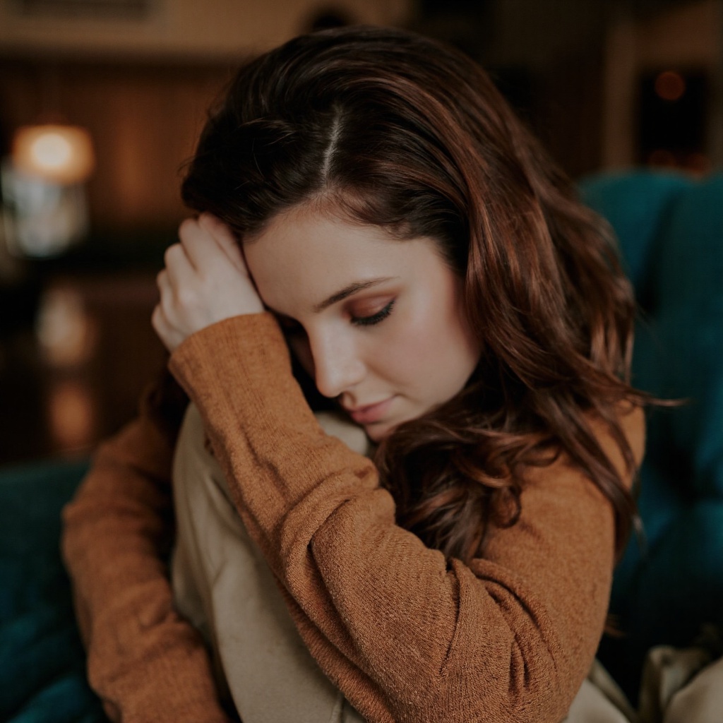 A portrait of sydney_sierota,  captured in a side profile. She wears a rust-colored,  long-sleeved sweater. Her dark hair...