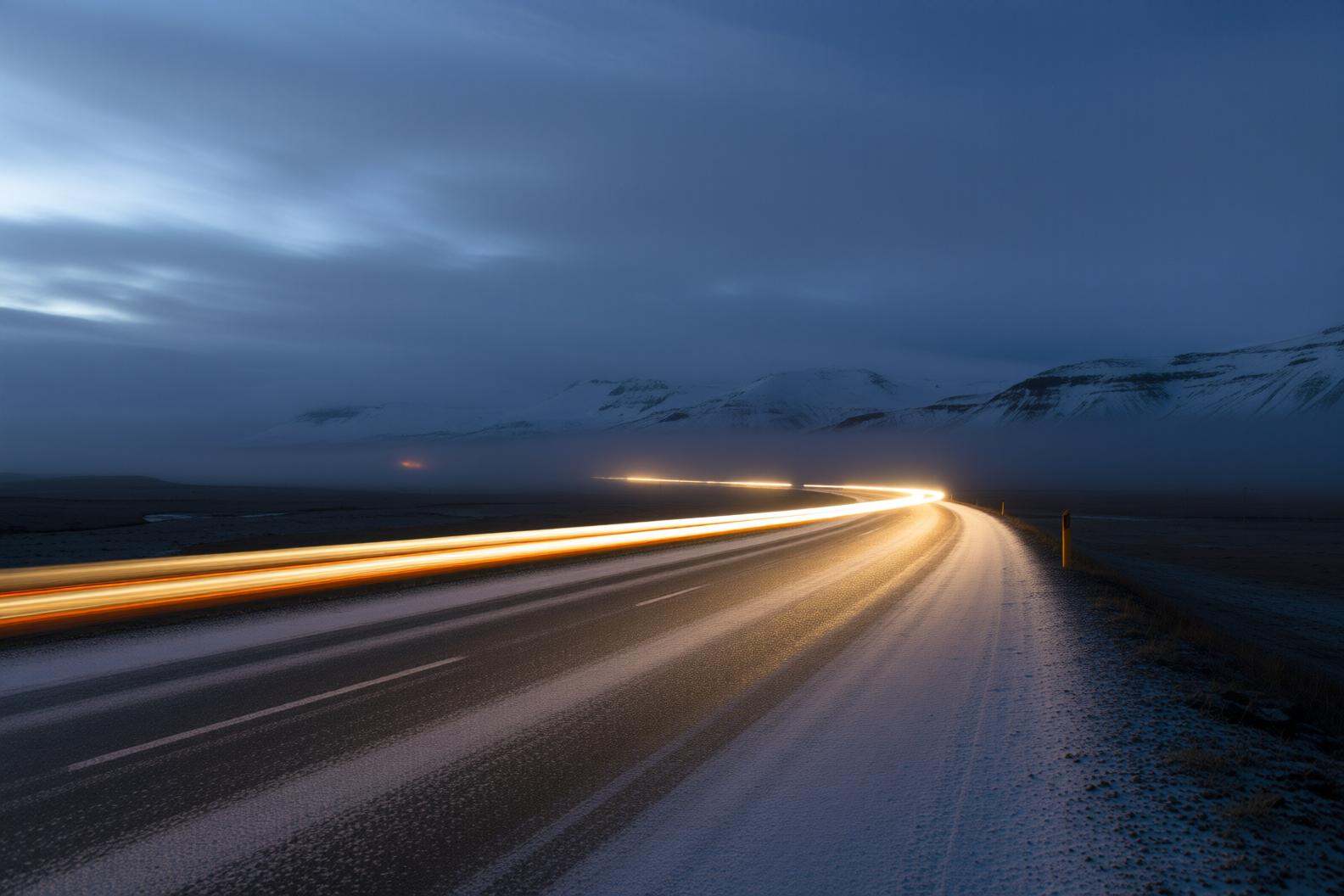 aurelmanea2q photography.A snowy landscape with a road curving into the distance. The road is partially covered with a thi...
