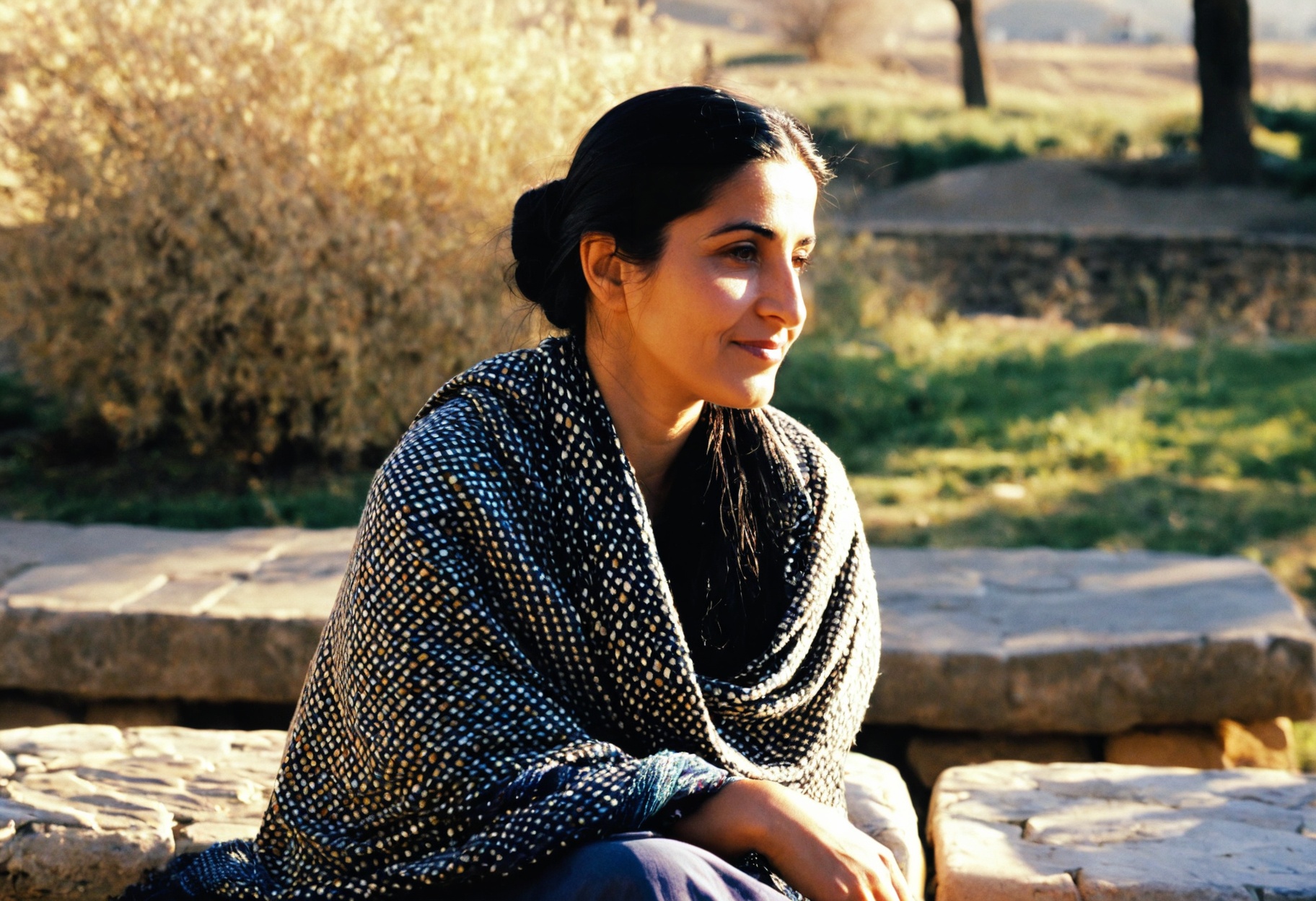 A portrait of a 33-year-old Kurdish woman seated on a stone bench,  her long black hair in a low bun and a patterned shawl...