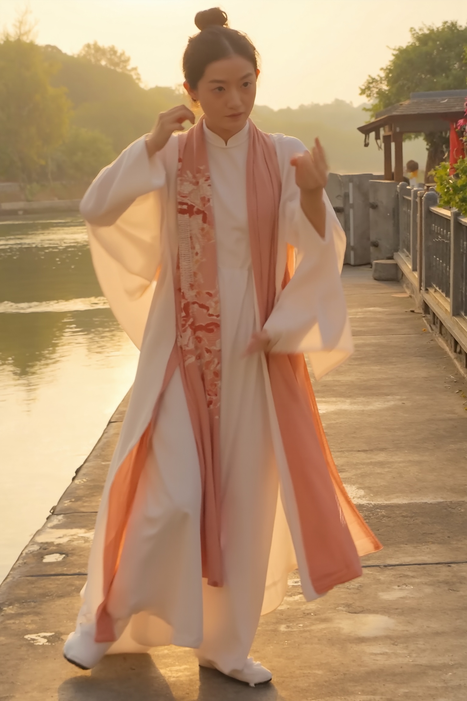 A beautiful woman in a traditional Chinese hanfu,  standing on a riverbank park in the early morning,  performing a gracef...