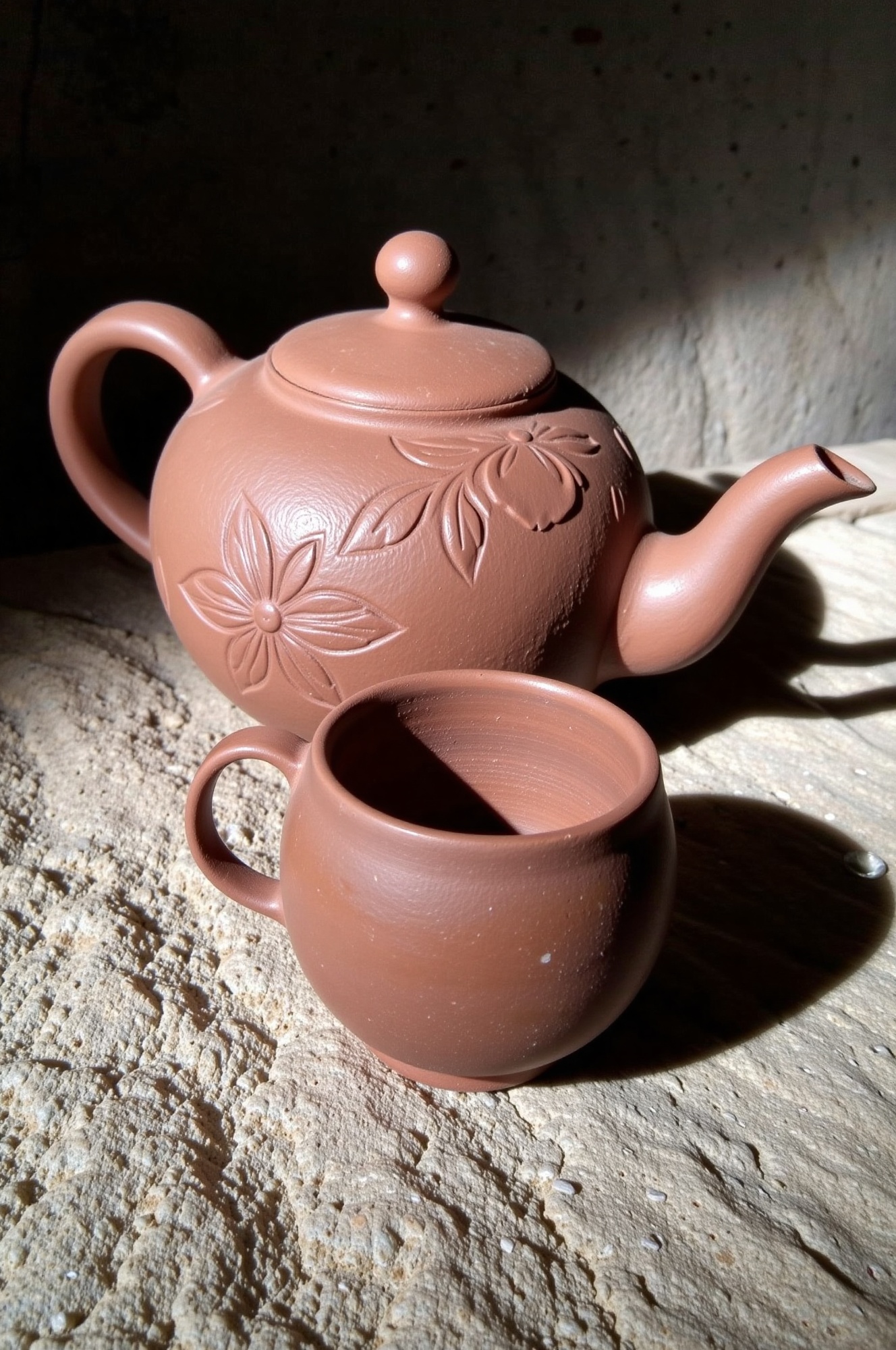 Commercial photograph of a traditional Indonesian teapot and cup set made of clay. The teapot is positioned slightly to th...