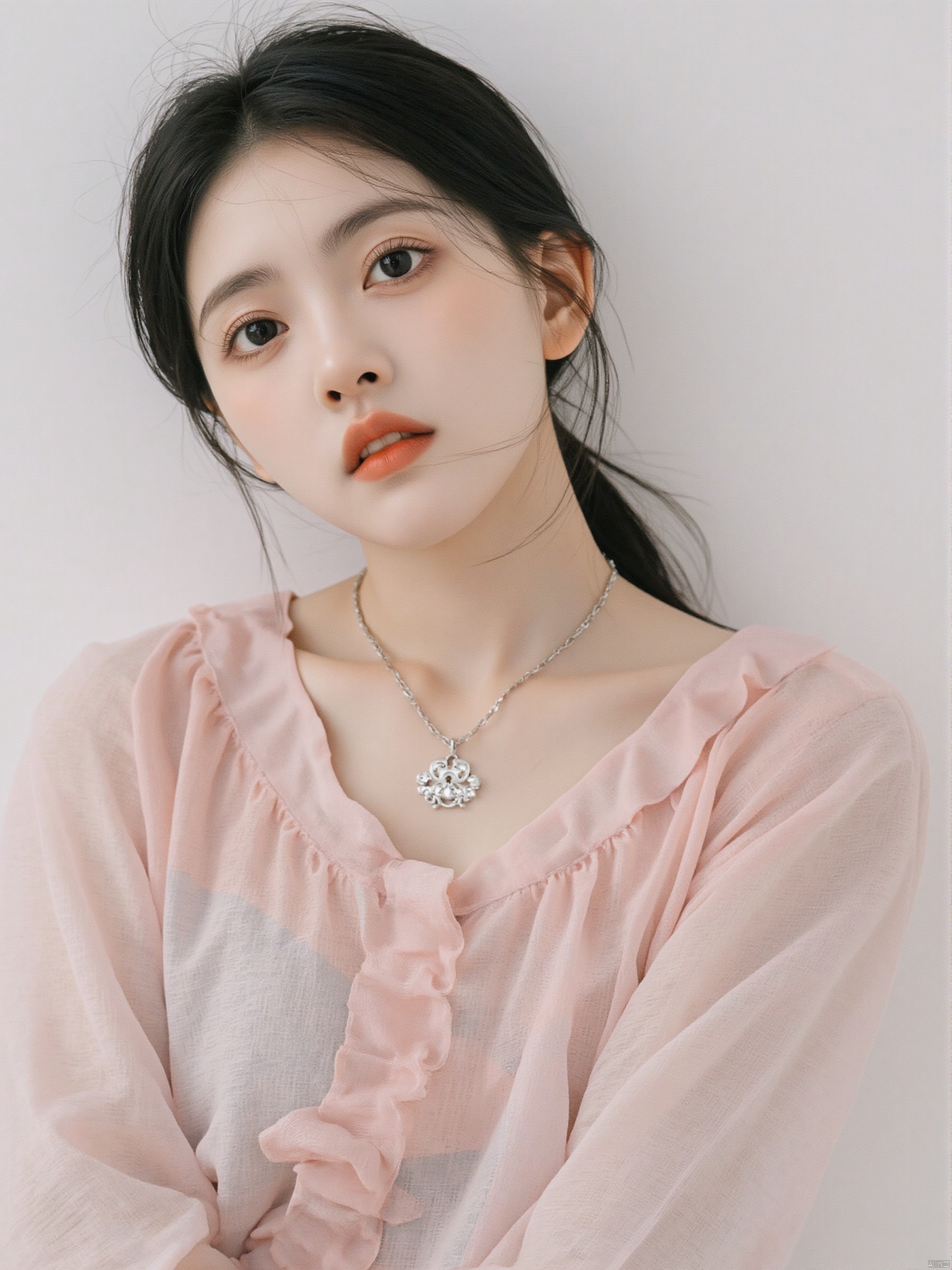 a close-up shot of a young Asian woman with dark brown eyes and a pink dress. Her hair is pulled back in a ponytail, cascading over her shoulders. She is wearing a silver necklace with a silver charm on it, adding a touch of charm to her outfit. The backdrop is a stark white wall, creating a stark contrast to the woman's outfit.