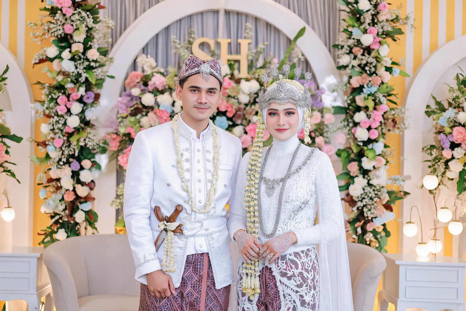 wedding photography,  the bride and groom standing in front of a wedding backdrop,  floral and SH in gold lettering on the...