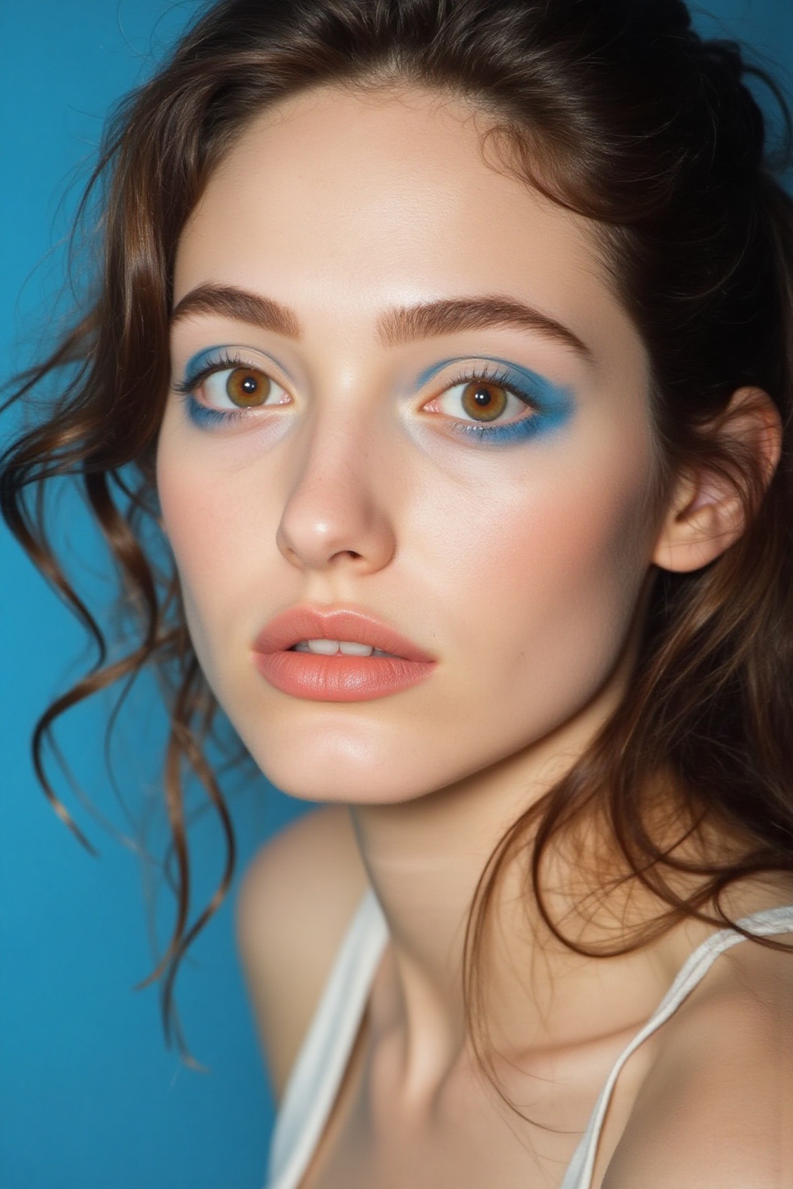 A high end beauty shot of a woman. model with blue eye shadows and subtle blush. dark brown eyes. Close up photo with a cl...