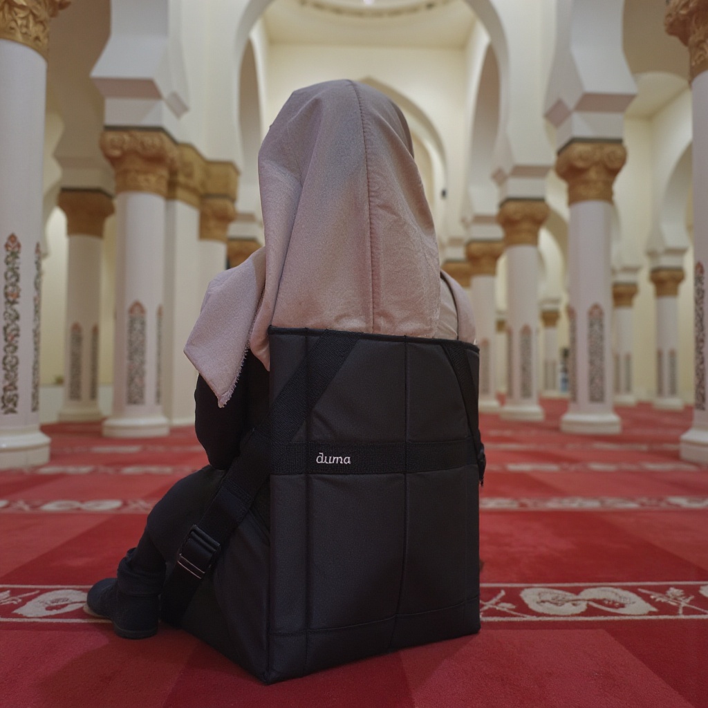 A hijabi woman sits serenely on the iconic a black floor duma chair labeled "duma",  its sleek black surface contrasting w...