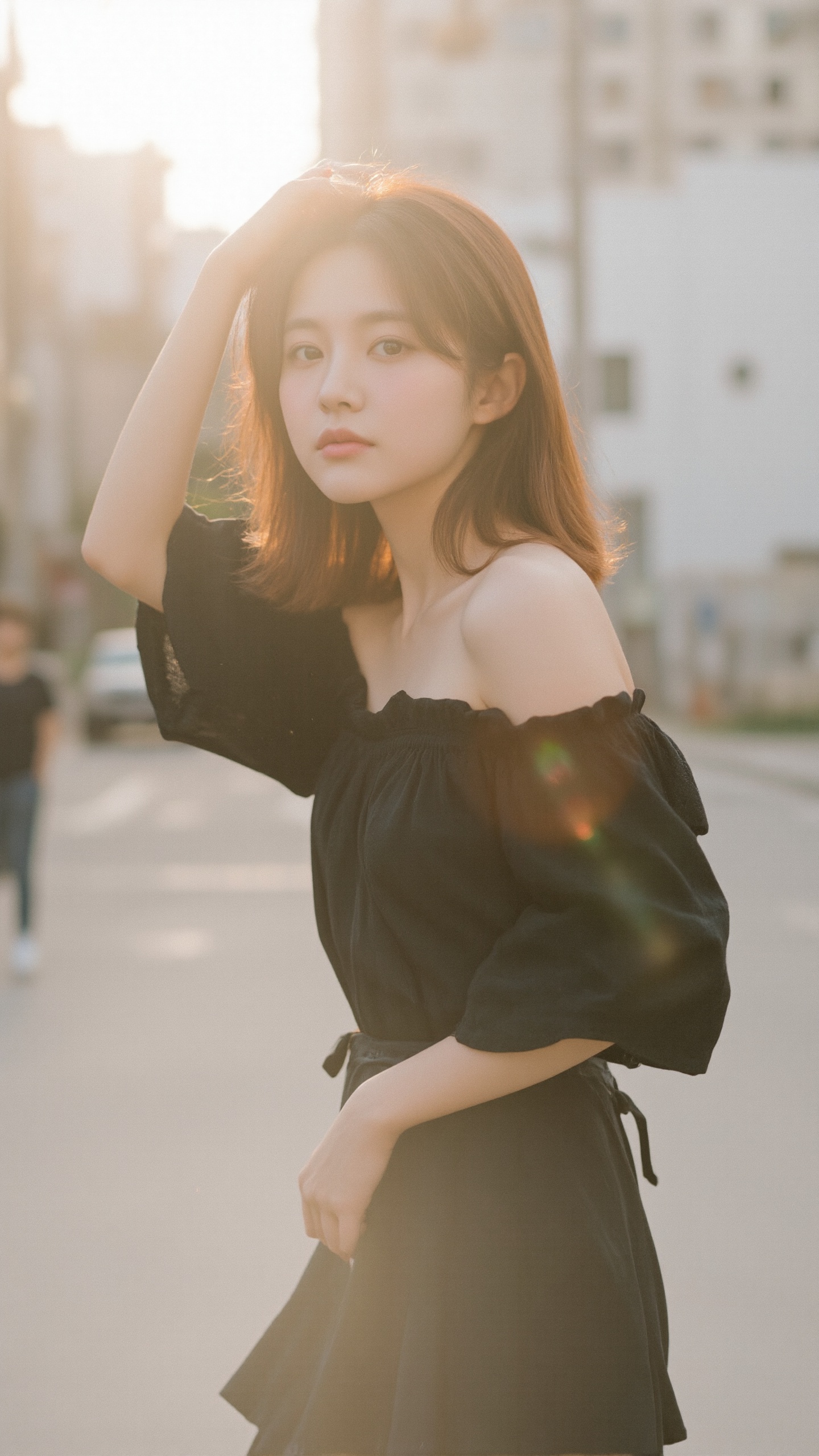 A soft-focus photograph captures a young Asian woman with light skin and shoulder-length auburn hair,  holding her hair wi...
