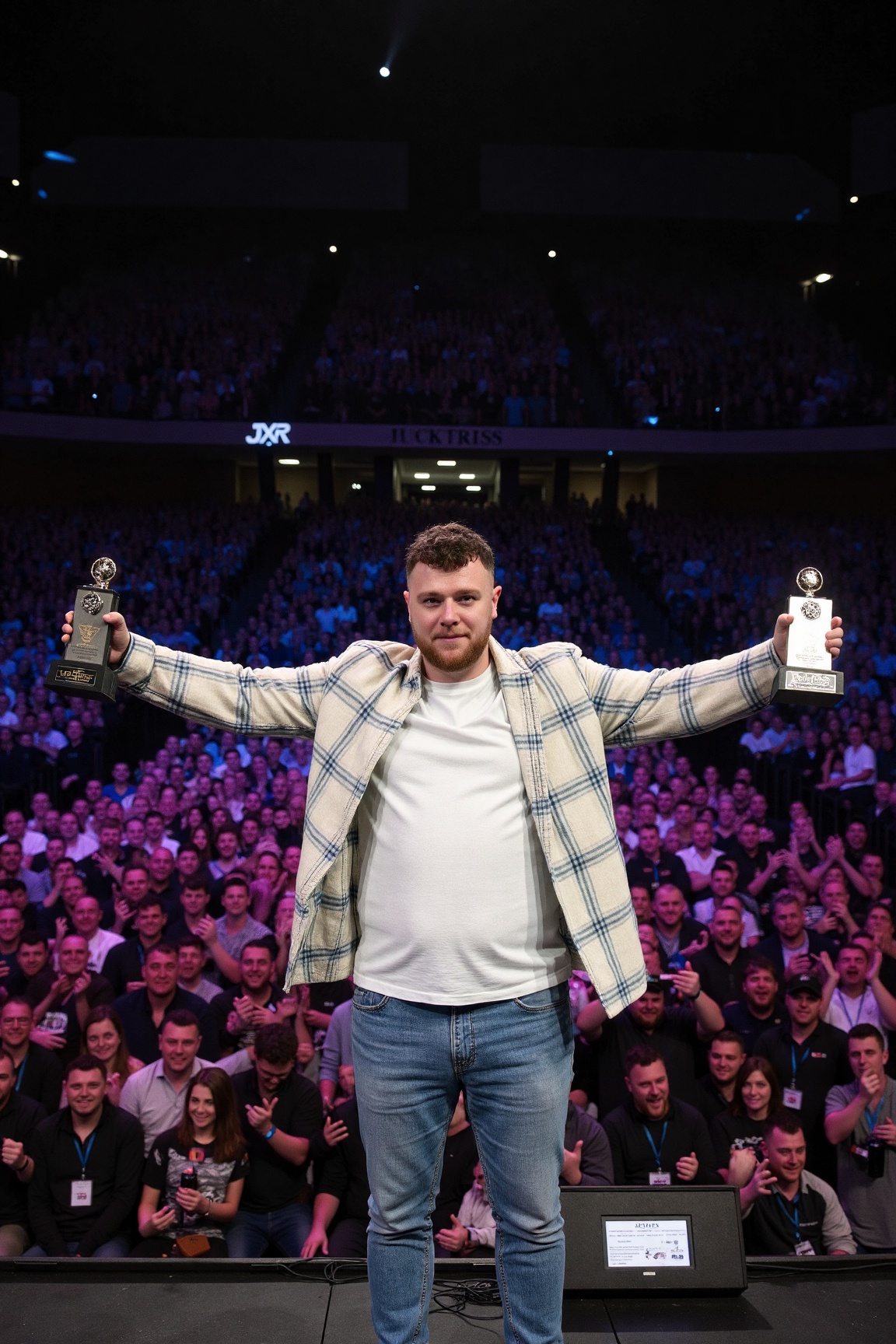 photo of jxr,  The image depicts a man standing on a stage with his arms raised high,  holding two trophies above his head...