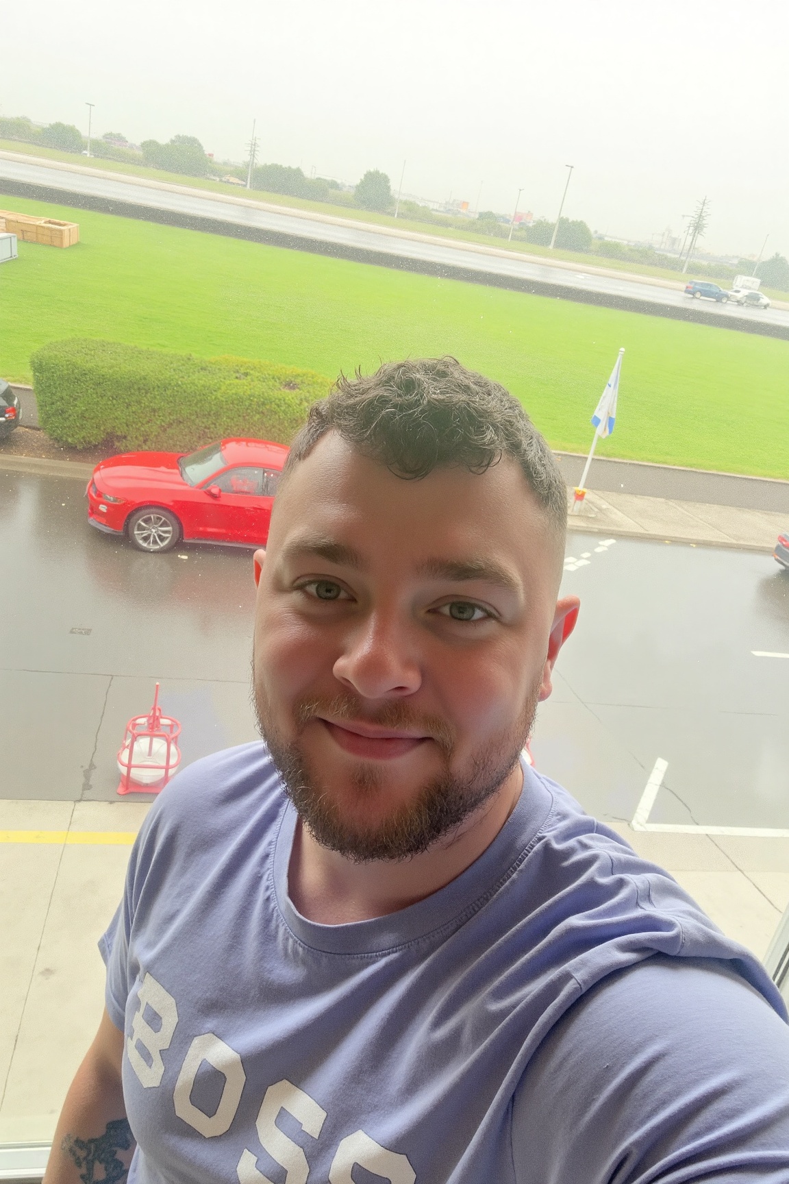 photo of jxr,  The image shows a person taking a selfie at what appears to be a race track or stadium. The background feat...