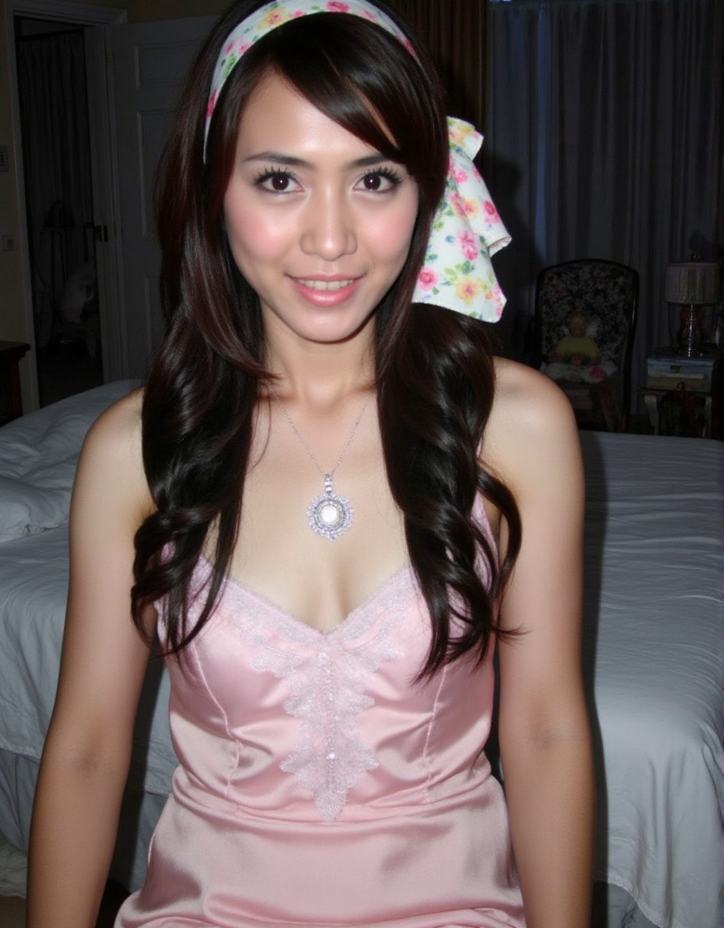 The image shows a person wearing a pink satin dress with lace detailing on the chest area. They have long,  wavy dark hair...