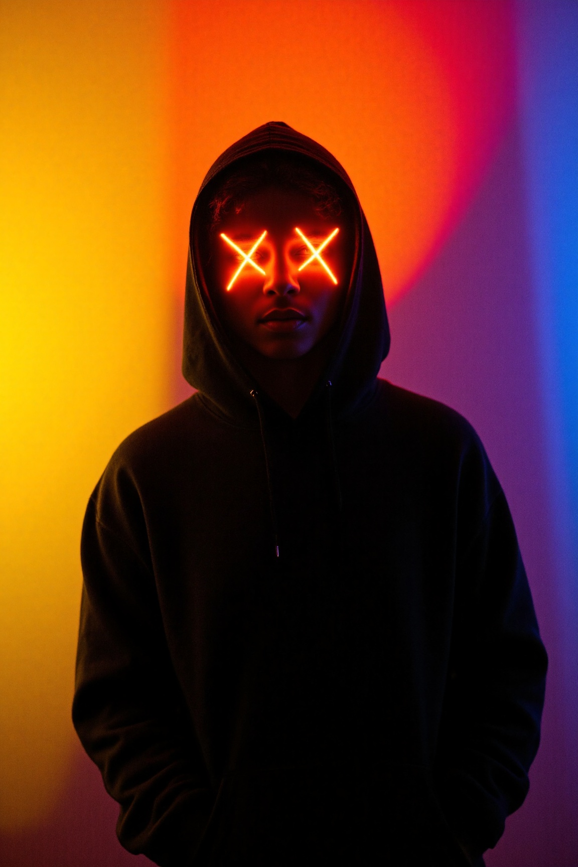 a person wearing a dark hoodie,  standing against a vibrant and colorful background. The person's face is partially obscur...