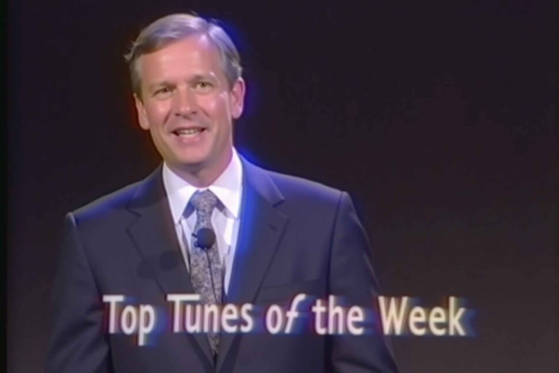 vhsc0re,  a vintage broadcast host in a suit and tie presents "Top Tunes of the Week,  " the entire dark scene defined by...