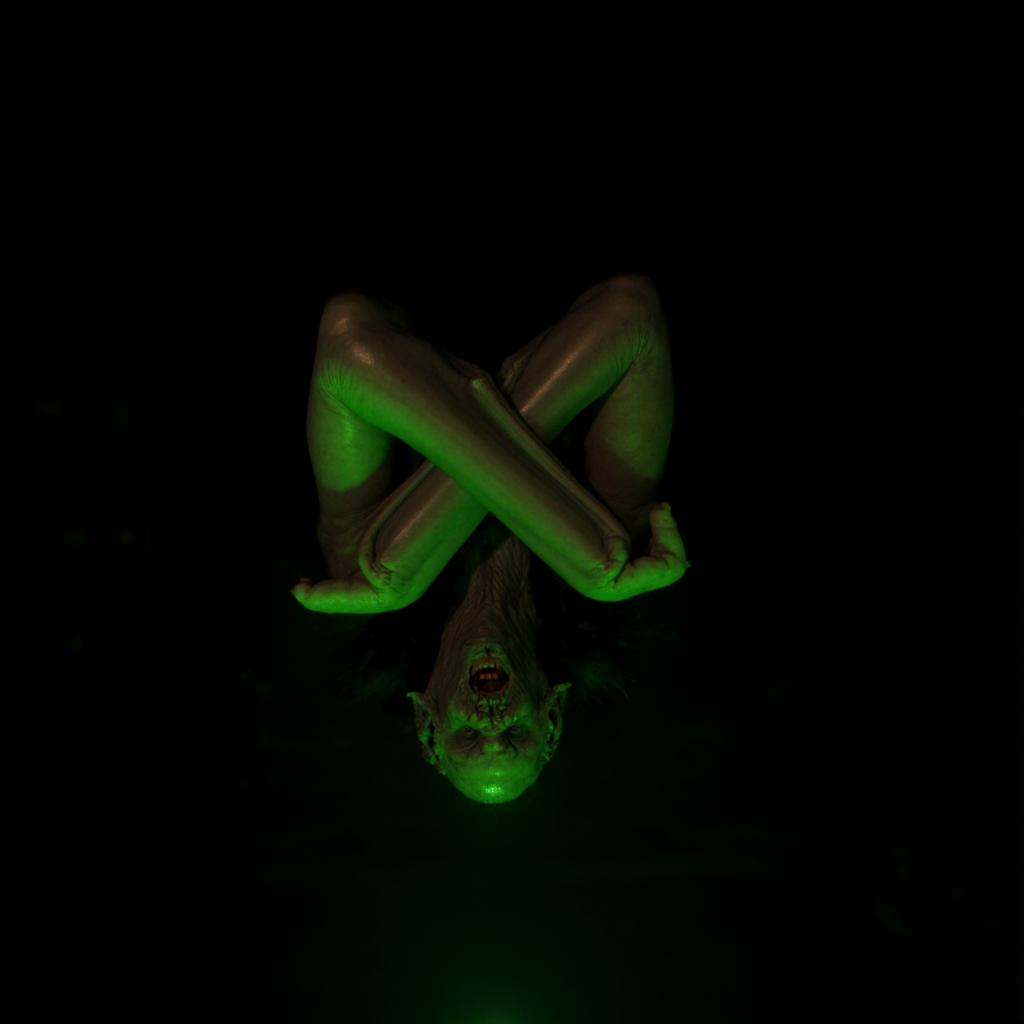 cinematic film still of Vampire Bat creature a bat creature with it's hands crossed hanged upside down from a sealing in t...