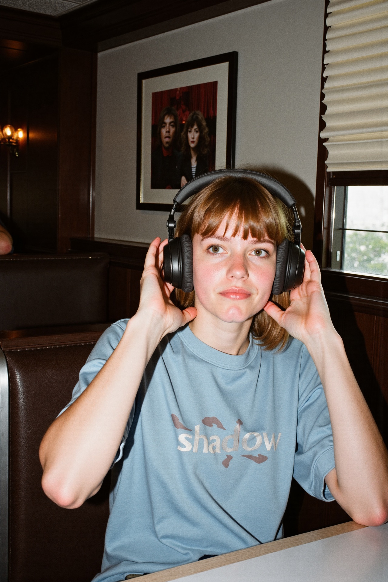 Prompt: A young woman with light skin and medium-length brown hair sits in a dimly lit diner wearing a light blue "shadowe...