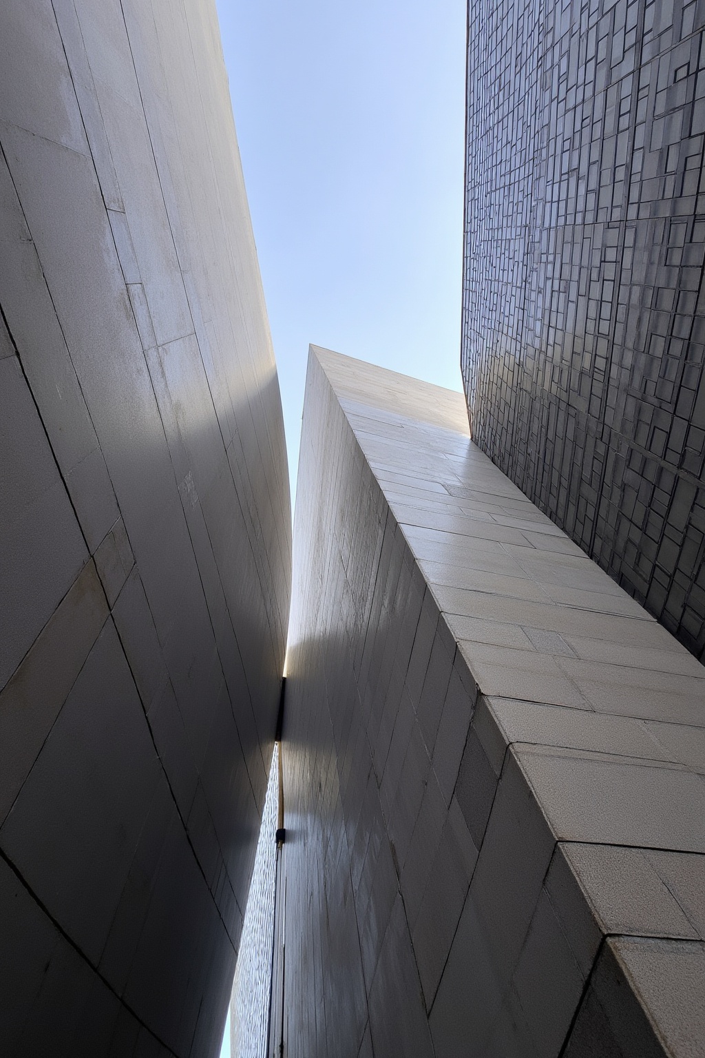 The image depicts a modern architectural structure with a geometric design. The structure is composed of large,  angular,...
