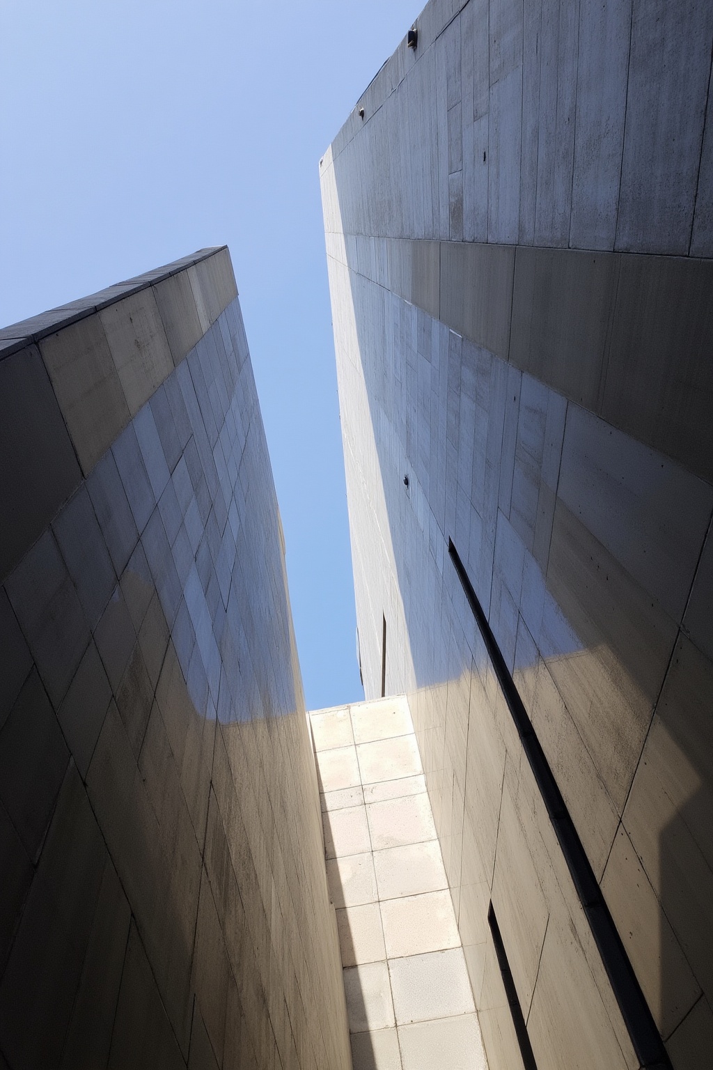 The image depicts a modern architectural structure with a geometric design. The structure is composed of large,  angular,...