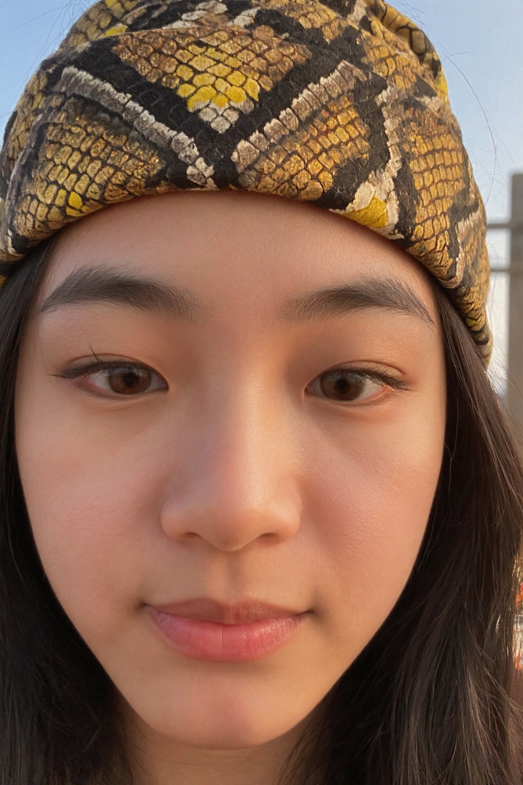 A close-up shot of a young woman's face,  her eyes gazing intensely into the distance. She wears a vibrant serpent-pattern...