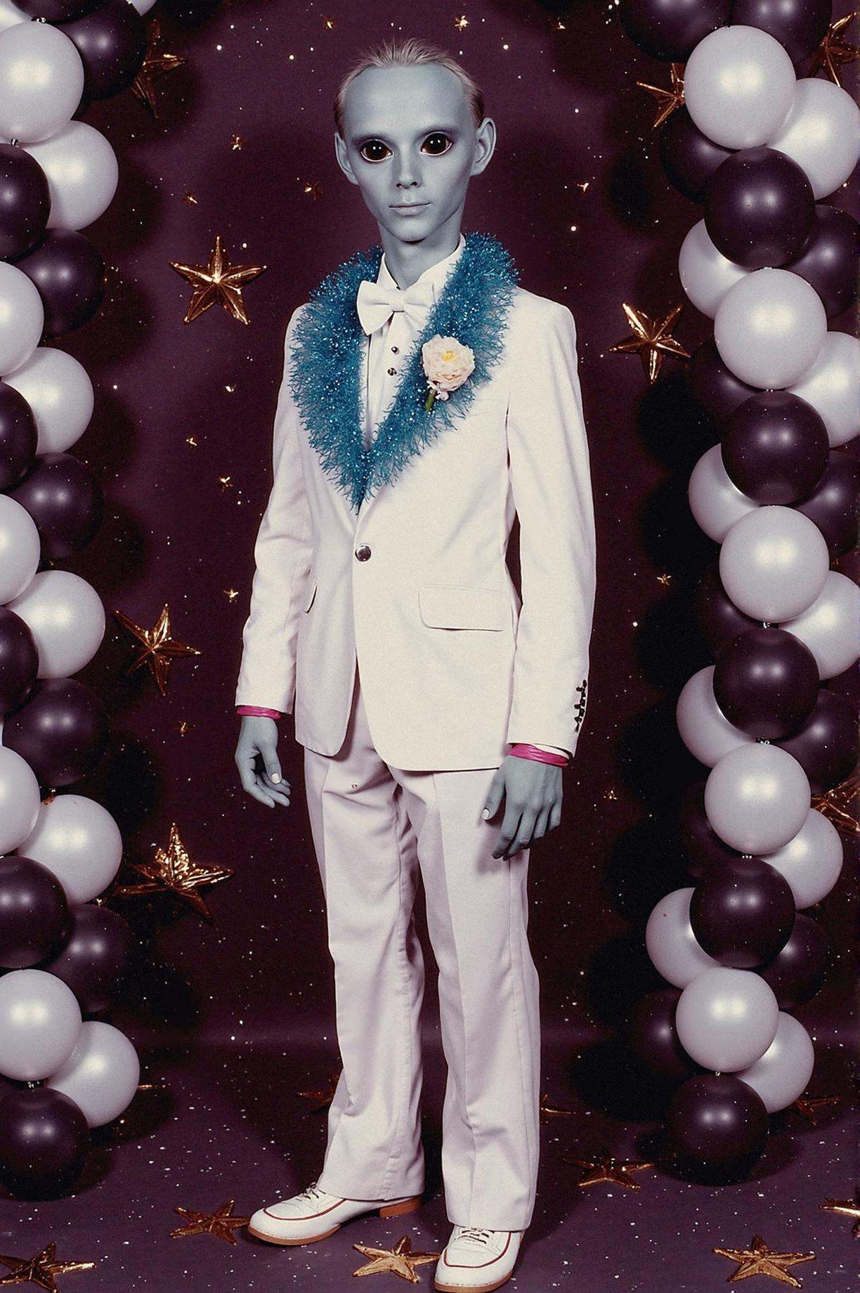 prom photo,  lanky grey alien with oversized black eyes wearing a white tuxedo with a blue ruffled shirt,  holding a corsa...