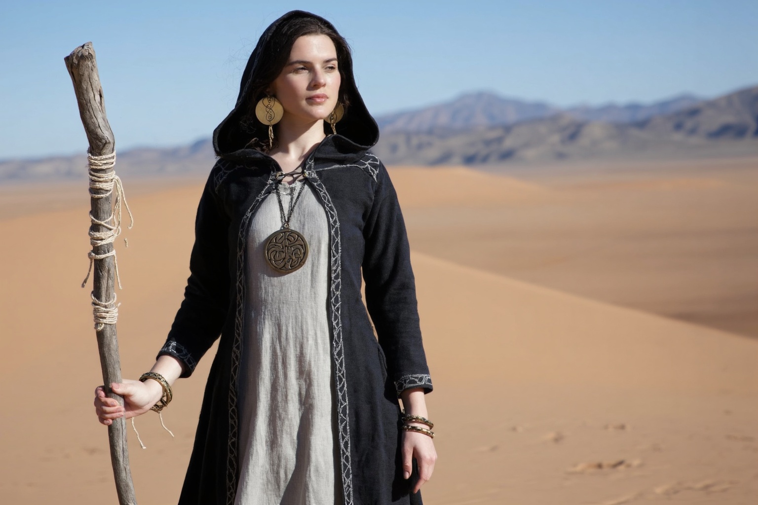 A high concept,  high quality medium shot shows a woman standing in a vast,  sun-drenched desert landscape under a clear o...