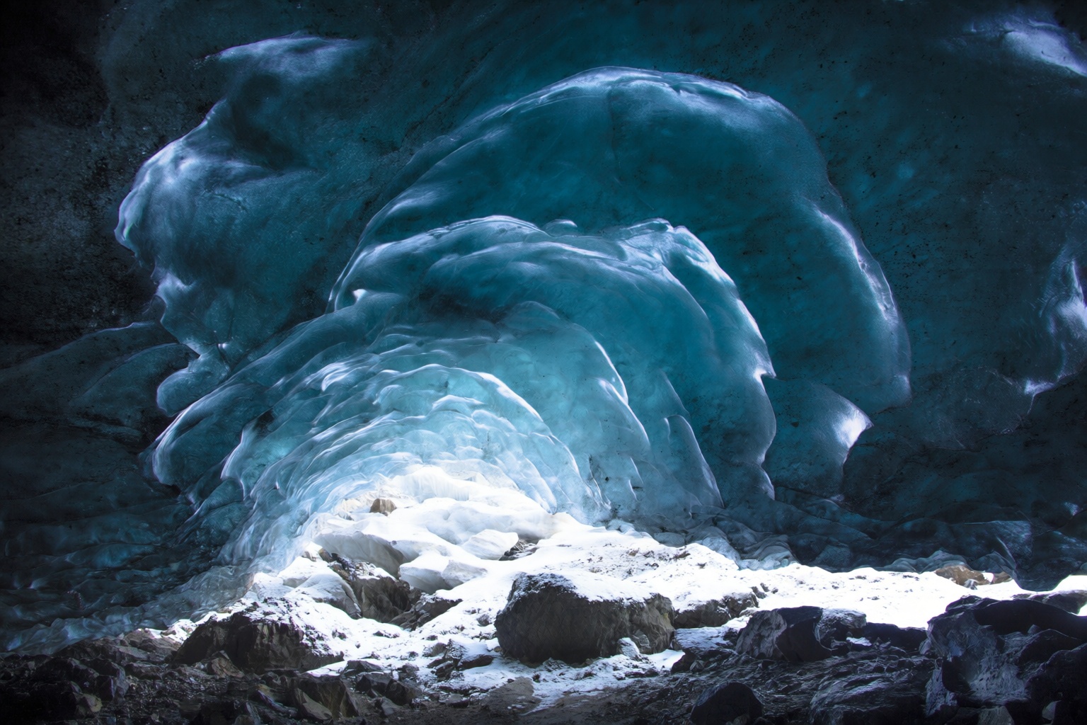 aurelmanea2q photography. An ice cave with a stunning display of blue ice formations. The ice has a smooth,  flowing appea...
